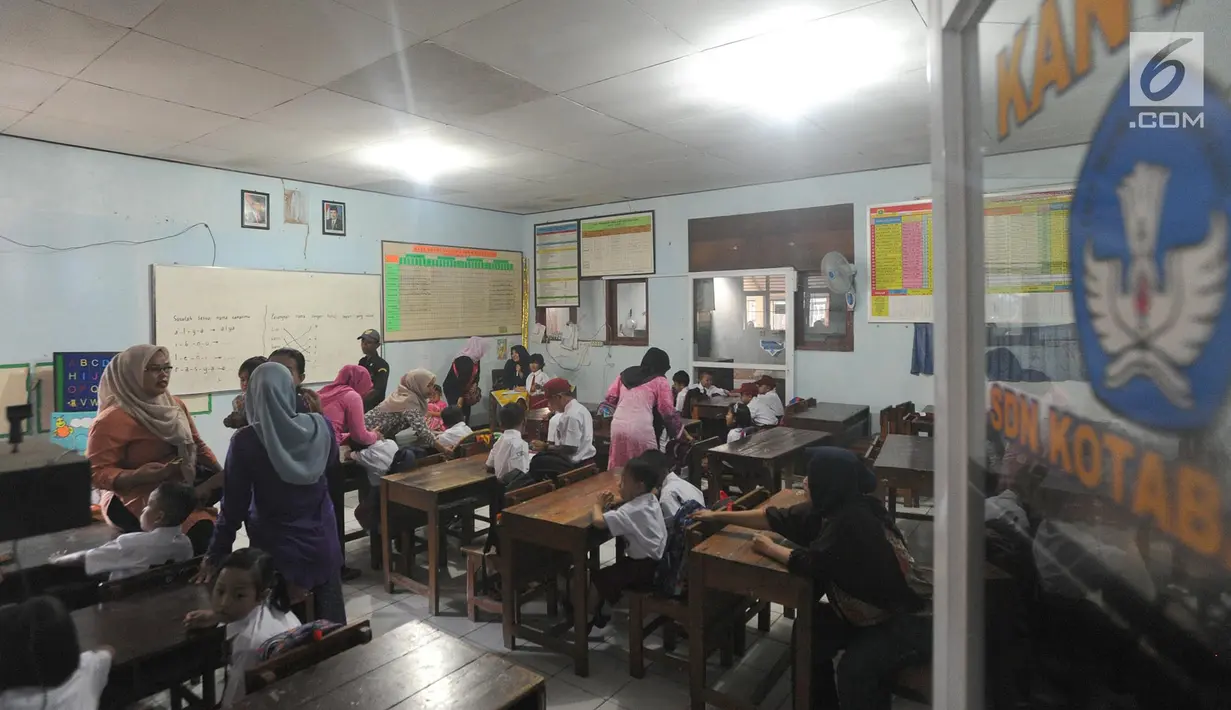 Para murid melakukan kegiatan belajar mengajar di ruang guru SD Negeri Kotabatu 08 Kecamatan Ciomas Kabupaten Bogor, Senin (23/7). Para murid secara bergantian menggunakan ruangan dengan kelas lain akibat ambruknya dua bangunan. (Merdeka.com/Arie Basuki)