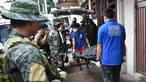 Personel polisi Filipina mengamati pekerja yang membawa jasad seorang napi yang tewas akibat kerusuhan di sebuah penjara di Filipina, Rabu (28/9). Selain menewaskan satu anggota geng narkoba, kerusuhan itu juga melukai tiga napi lainnya. (TED Aljibe/AFP)