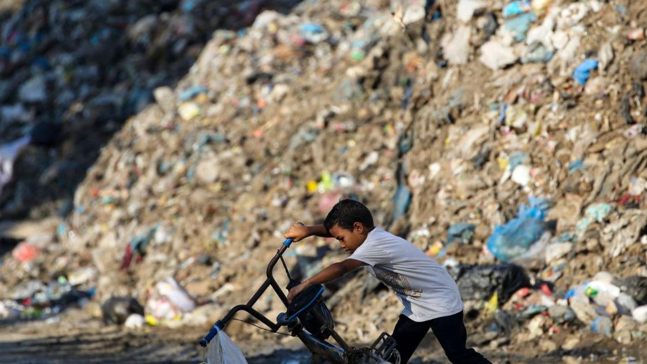 Seorang anak mendirikan sepedanya saat bermain di dekat sampah yang menggunung di kamp pengungsian&nbsp;Al-Maghazi di Jalur Gaza, Palestina, pada 2 Agustus 2024. Serangan brutal yang terus dilancarkan Israel membuat kehidupan warga Palestina di Jalur Gaza