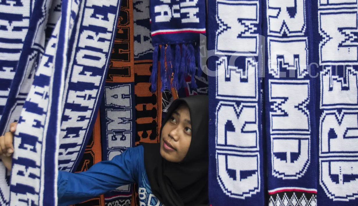 Seorang Aremanita melihat-lihat syal Arema FC yang dijual oleh pedagang kaki lima jelang laga semifinal Piala Presiden 2017 antara Arema FC melawan Semen Padang di sekitar Stadion Kanjuruhan, Malang, Jawa Timur, Minggu (5/3/2017). (Bola.com/Vitalis Yogi T