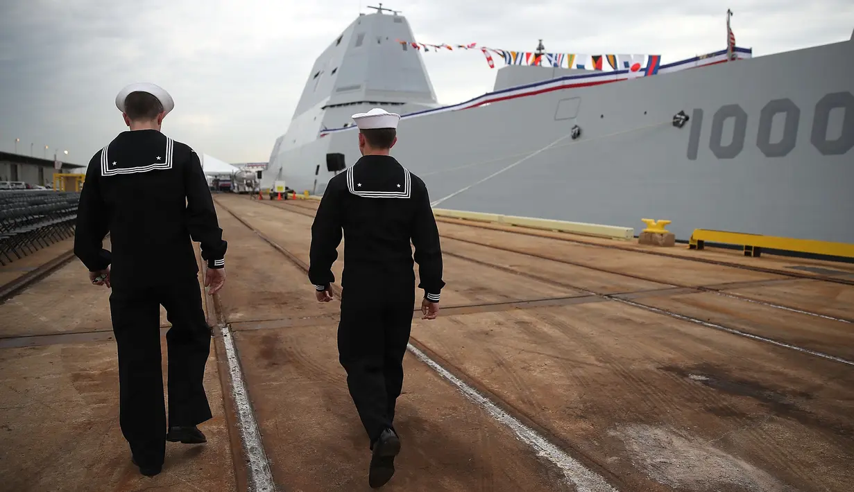 Dua pelaut berjalan disamping Kapal USS Zumwalt di Baltimore, Maryland, AS (13/10). Kapal senilai USD 4,4 miliar ini memiliki bentuk yang gagah dan dilengkapi sistem persenjataan canggih. (AFP Photo/Mark Wilson)