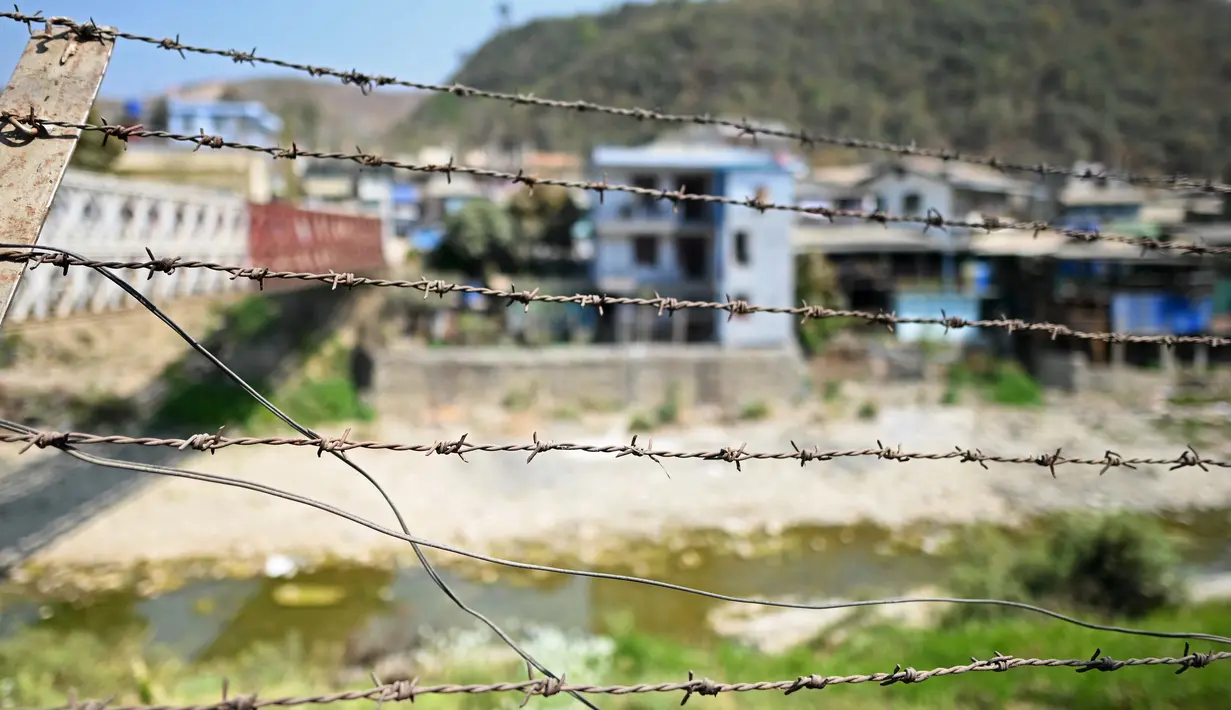 Rumah-rumah di sisi Myanmar terlihat dari balik kabel berduri yang dipasang di sepanjang tepi Sungai Tiau, perbatasan alami antara India dan Myanmar, Zokhawthar, negara bagian Mizoram (15/3/2021).  (AFP/Sajjad Hussain)