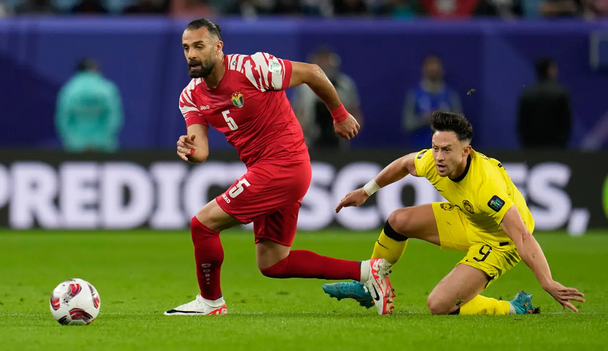 Pemain Yordania Yazan Alarab (kiri) mengincar bola saat pemain Malaysia Darren Lok terjatuh pada pertandingan sepak bola Grup E Piala Asia di Stadion Al Janoub, Al Wakrah, Qatar, Senin (15/1/2024). (AP Photo/Aijaz Rahi)