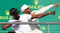 Pembalap Marcedes, Lewis Hamilton berpose dengan mantan atlet lari cepat asal Jamaika, Usain Bolt di atas podium setelah berhasil memenangi balapan GP Amerika Serikat di Circuit of Americas, Minggu (22/10). (CLIVE ROSE / GETTY IMAGES / AFP)