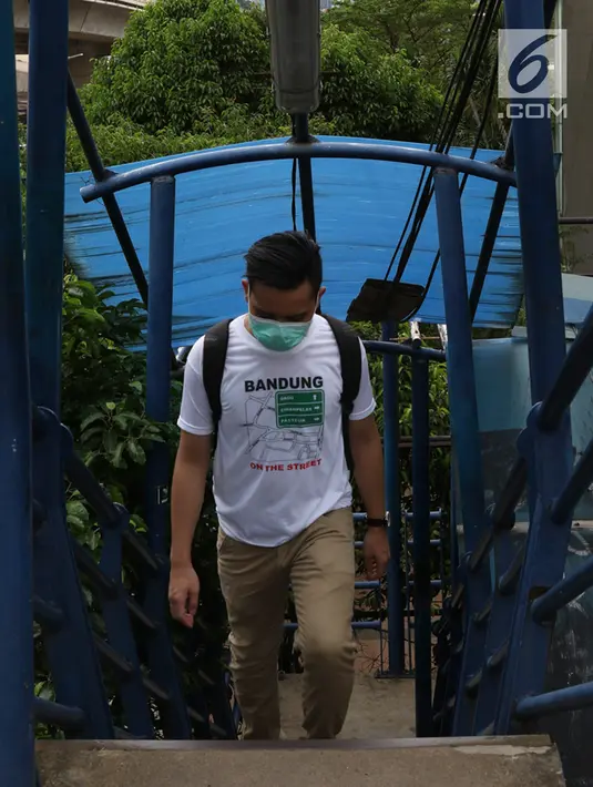 Pejalan kaki melintasi JPO yang atapnya rusak di kawasan Kuningan, Jakarta, Minggu (10/2). Kondisi JPO yang sebagian atapnya hilang tersebut mengganggu kenyamanan pejalan kaki, terutama saat hujan. (Liputan6.com/Immanuel Antonius)