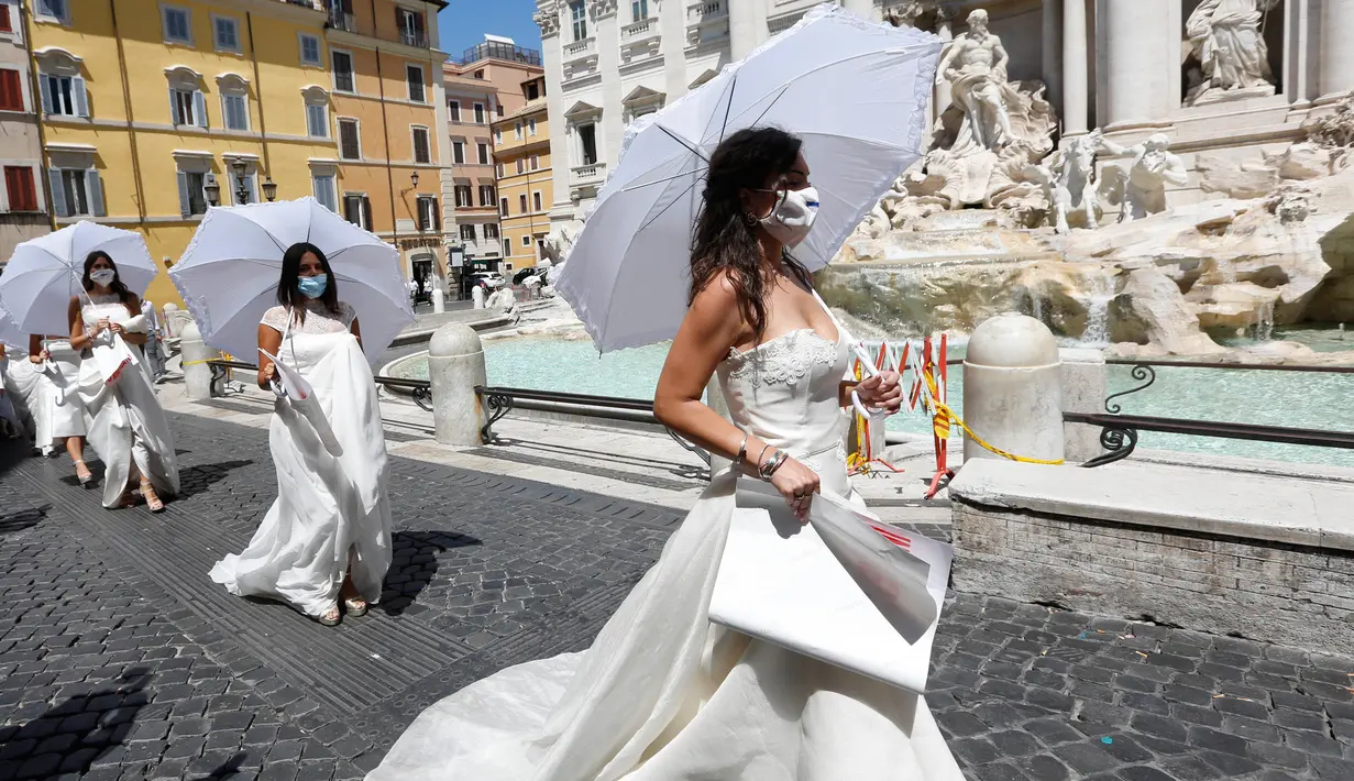 Para perempuan yang upacara pernnikahannya ditunda atau dibatalkan akibat pandemi covid-19 melakukan protes di Trevi Fountain, Roma, Selasa (7/7/2020). Mereka memprotes kebijakan pemerintah Italia yang masih melarang adanya acara pernikahan, meski lockdown sudah dilonggarkan. (AP/Riccardo De Luca)
