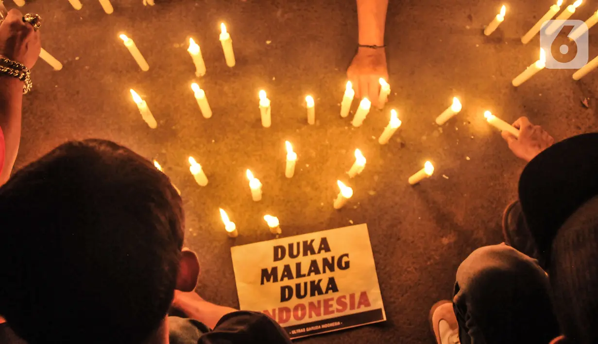 Massa yang tergabung dalam Ultras Garuda Jakarta mengikuti aksi menyalakan lilin dan tabur bunga untuk korban kerusuhan Stadion Kanjuruhan Malang di depan Stadion Gelora Bung Karno (GBK), Jakarta, Minggu (2/10/2022). Aksi tersebut sebagai aksi solidaritas antar suporter dan bentuk keprihatinan atas tragedi kerusuhan suporter sepak bola di Stadion Kanjuruhan Malang. (merdeka.com/Iqbal S Nugroho)