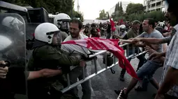Pengunjuk rasa anti-Eropa berebut atribut dengan petugas kepolisian di Athena, Yunani, (2/7/2015). PM Alexis Tsipras mengatakan tutupnya bank tidak akan lama setelah adanya kontrak baru dengan kreditur setelah referendum. (REUTERS/Panayiotis Tzamaros)