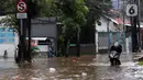 Pengendara menaiki sepeda motornya melewati banjir yang menggenangi kawasan Jalan Wolter Monginsidi Jakarta dan sekitarnya, Sabtu (20/2/2021). Hujan yang mengguyur Jakarta sejak Jumat (19/2) membuat sejumlah titik di Jakarta terendam banjir. (Liputan6.com/Helmi Fithriansyah)