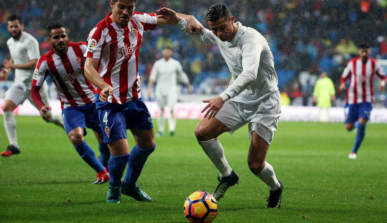 Penyerang Real Madrid, Cristiano Ronaldo, berusaha melewati hadangan pemain Sporting Gijon. Gol kedua Ronaldo tercipta pada menit ke-18 melalui umpan Nacho. (Reuters/Susana Vera)