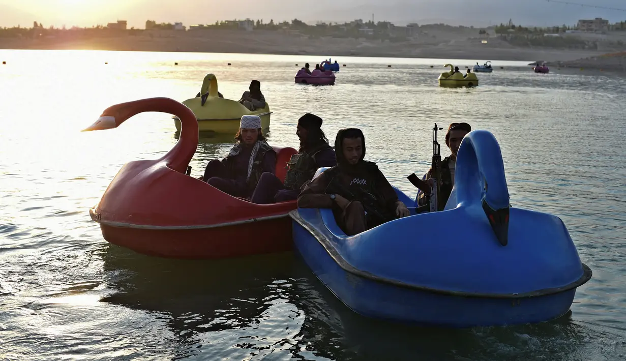 Sejumlah pasukan Taliban saat menaiki perahu kayuh di Danau Qargha di sebuah pekan raya di Kabul barat (28/9/2021). Sambil membawa senjata laras panjang sambil berjaga, mereka mengayuh perahu bebek memutari danau. (AFP/Wakil Kohsar)