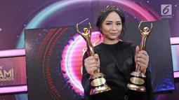 Penyanyi Gita Gutawa berpose memenggang piala usai meraih penghargaan Anugerah Musik Indonesia (AMI) Awards 2017 di Teater Garuda TMII, Jakarta, Kamis (16/11). (Liputan6.com/Herman Zakharia)