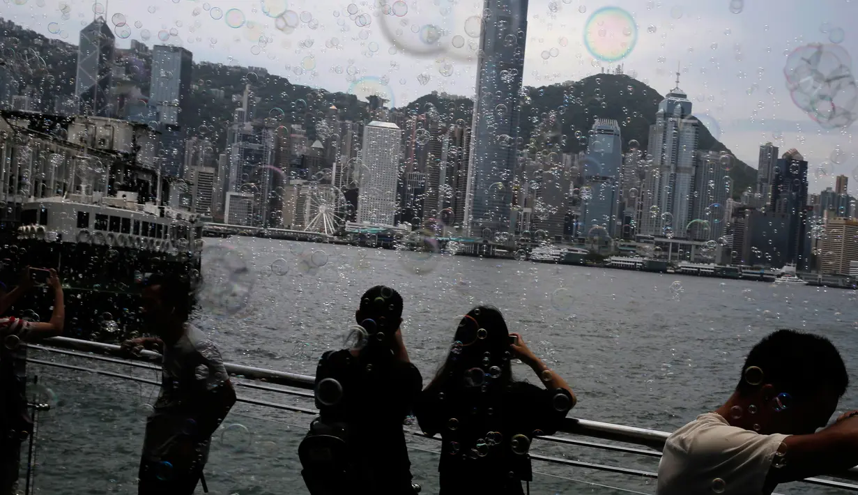 Pengunjung mengambil gambar gelembung yang berterbangan selama pertunjukan seni Bubble Up yang dibuat oleh seniman asal Jepang, Shinji Ohmaki, di Hong Kong, 2 Agustus 2017. (AP Photo/Kin Cheung)
