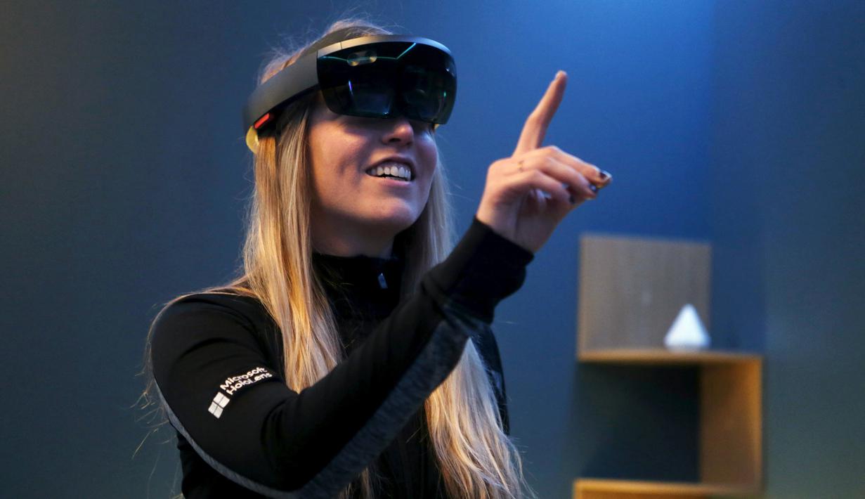 Pegawai Microsoft tersenyum saat memakai HoloLens selama Microsoft Build 2016 Developers Conference di San Francisco, California (30/3).  Dengan mengunakan HoloLens pemakai seperti 'berkunjungan' di beberapa situs di Mars. (REUTERS/Beck Diefenbach)