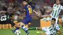 Lionel Messi (tengah) mengecoh kiper dan pemain Real Betis saat melakukan tembakan ke arah gawang pada lanjutan La Liga Spanyol di Camp Nou stadium, Barcelona, (20/8/2017). Barcelona menang 2-0. (AFP/Lluis Gene)