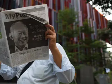 Seorang pria membaca koran setelah sehari meninggalnya mantan PM Singapura, Lee Kuan Yew, Singapura, Selasa (24/3/2015). Lee meninggal pada hari Senin (23/3) di usia 91 tahun dan wajahnya menghiasi berbagai media cetak Singapura. (AFP PHOTO/Mohd RASFAN)