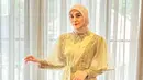 Fenita Arie dalam balutan abaya berwarna kuning yang super cantik. Abaya ini memiliki detail cape sebagai atasan, diberi tambahan belt dan payet batu sebagai pemanis. Fenita memadukan penampilannya dengan hijab berwarna cokelat muda yang serasi. Foto: Instagram.