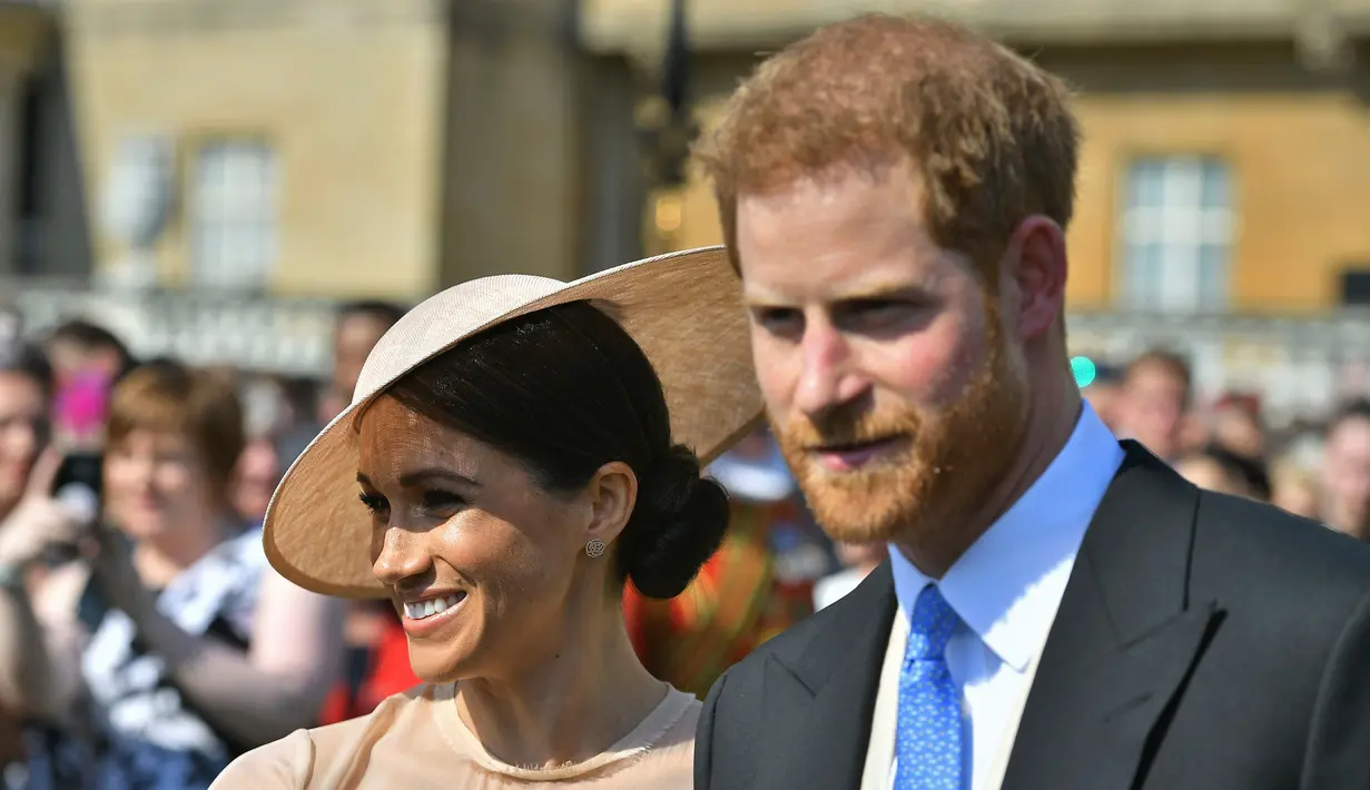Pangeran Harry dan Meghan Markle menghadiri pesta kebun Istana Buckingham di London, Selasa (22/5). Meghan Markle meninggalkan tampilan rambut messy bun andalannya, untuk beralih gaya rambut sleek dengan bun di samping. (Dominic Lipinski/Pool via AP)