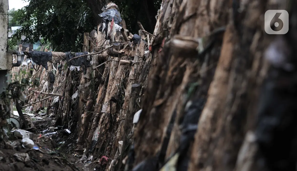 Kondisi tanggul kayu yang rusak dan penuh sampah di bantaran Kali Ciliwung, Rawajati, Pancoran, Jakarta, Minggu (5/1/2020). Tanggul dari kayu dolken dan karung pasir yang baru dibangun pada akhir Desember 2019 itu rusak hingga dipenuhi sampah akibat terjangan arus banjir. (merdeka.com/Iqbal Nugroho)