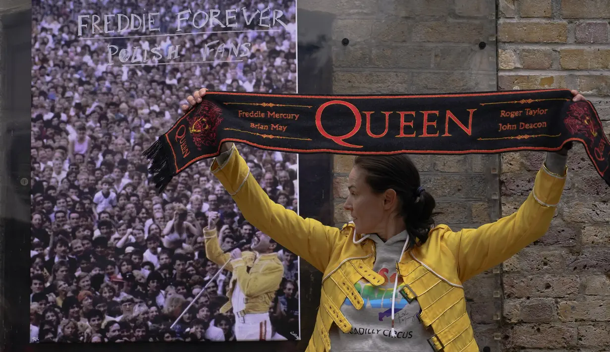 Penggemar memegang syal band rock Inggris Queen, saat berpose di luar rumah mendiang Freddie Mercury, pada peringatan 30 tahun kematiannya, di London, Rabu (24/11/2021). Freddie Mercury, penyanyi yang juga pentolan grup band Queen meninggal dunia pada 24 November 1991. (AP Photo/Alberto Pezzali)