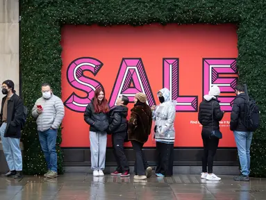 Pembeli, beberapa mengenakan masker, mengantre untuk memasuki department store Selfridges menjelang penjualan Boxing Day di pusat kota London, Minggu (26/12/2021).  'Boxing Day' adalah hari saat toko-toko di Inggris menggelar diskon besar-besaran, sehari setelah Natal. (Niklas HALLE'N / AFP)