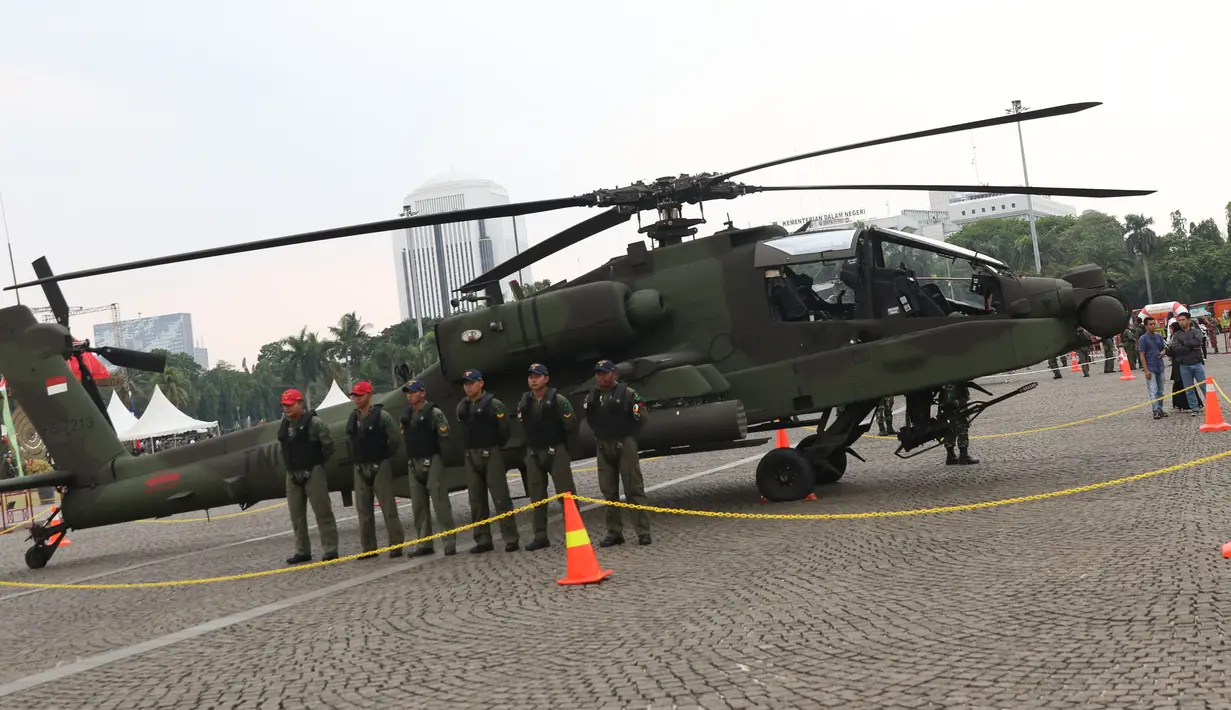 Tim penerbang berada di sisi helikopter Apache yang dipamerkan pada pameran Alat Utama Sistem Persenjataan TNI di Kawasan Monas, Jakarta, Kamis (27/9). TNI memiliki delapan helikopter Apache AH 64E buatan Amerika Serikat. (Liputan6.com/Helmi Fithriansyah)