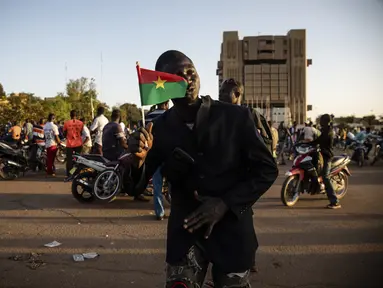 Pendukung gerakan Save Burkina Faso memegang bendera nasional setelah Letnan Kolonel Paul Henri Sandaogo mengumumkan telah mengambil alih kendali negara di Ouagadougou, Senin (24/1/2022). Militer Burkina Faso mengklaim berhasil mengambil alih pemerintahan dan mengudeta presiden. (AP/Sophie Garcia)