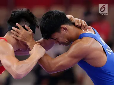 Pegulat putra Indonesia, Muhammad Aliansyah dan Zhang Gaoquan dari China saling mengunci saat bertarung pada kelas putra 67 Kg Asian Games 2018 di arena gulat JCC Senayan, Selasa (21/8). (Liputan6.com/Fery Pradolo)