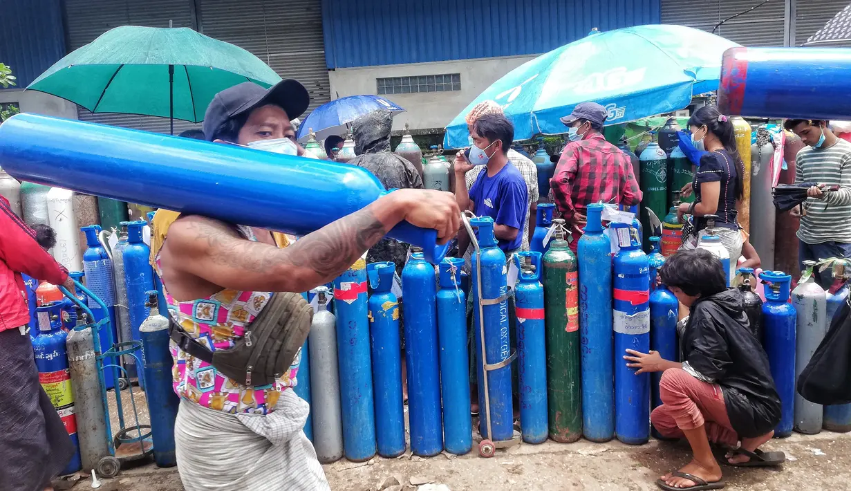 Seorang pria membawa tabung oksigen di luar pabrik oksigen Naing di zona industri South Dagon di Yangon, Myanmar, Rabu (28/7/2021). Myanmar saat ini dilanda lonjakan jumlah kasus COVID-19 dan kematian yang sangat membebani infrastruktur medis negara itu. (AP Photo)