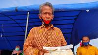 Sutoyo (52), salah satu petani padi di Desa Nusakarta Jalur 27 Kecamatan Air Sugihan Kabupaten OKI Sumsel yang menunjukkan beras hasil panennya yang mengalami penurunan harga jual (Liputan6.com / Nefri Inge)