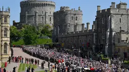 Pangeran Harry dan istri, Meghan Markle menaiki kereta kencana setelah upacara pernikahan mereka di Kastil Windsor, Inggris, Sabtu (19/5). Warga Inggris bersuka cita menyambut pernikahan Pangeran Harry dengan Meghan Markle. (TOBY MELVILLE/POOL/AFP)