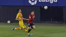 Penyerang Osasuna, Kike Barja membawa bola dari kejaran gelandang Barcelona, Sergio Busquets pada pertandingan lanjutan La Liga Spanyol di stadion El Sadar di Pamplona, Minggu (7/3/2021). Barcelona sukses menjaga jarak dua poin dengan pemuncak klsemen Atletico Madrid. (AP Photo/Alvaro Barrientos)