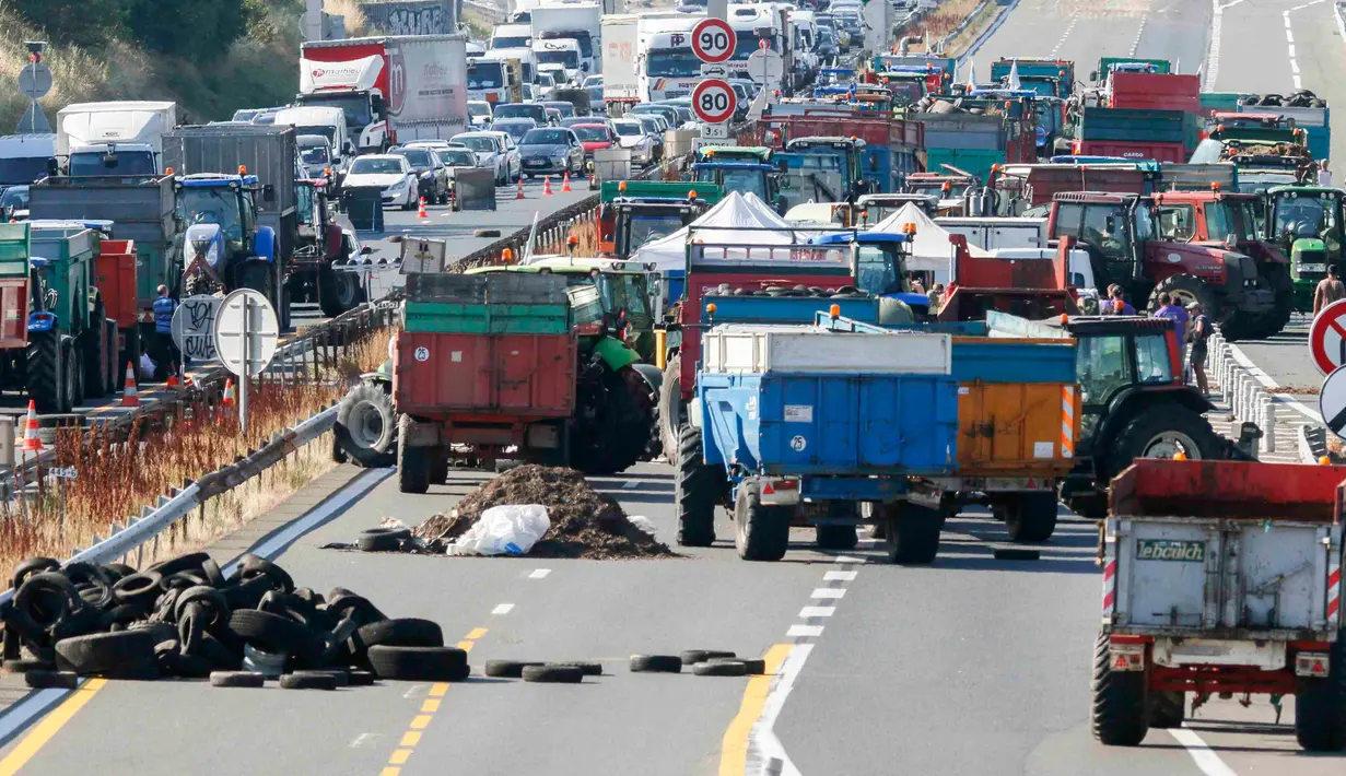 Puluhan traktor berjejer menutupi jalan raya A6 di Limonest, dekat Lyon, Prancis (23/7/2015). Petani Perancis memprotes kembali ketidak seimbangan keuntungan yang diperoleh antara petani dan pengecer. (REUTERS/Robert Pratta)