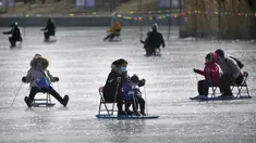 Seorang wanita dan anak-anak mendorong kursi es melintasi kolam beku di taman umum di Beijing, Selasa (17/1/2023). China telah mengumumkan penurunan populasi pertamanya dalam beberapa dasawarsa seiring bertambahnya usia negara terpadat di dunia dan angka kelahirannya yang menurun. (AP Photo/Mark Schiefelbein)
