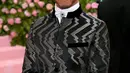 Pembalap Mercedes, Lewis Hamilton saat menghadiri Met Gala 2019 di Metropolitan Museum of Art di New York, AS (6/5/2019). Pria 34 asal Inggris ini tampil dengan jas hitam memamerkan desain zig-zag perak dan celana yang senada. (AFP Photo/Neilson Barnard)