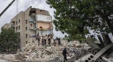 Petugas penyelamat berdiri di atas puing-puing di tempat kejadian setelah serangan rudal Rusia mengenai blok apartemen perumahan, di Chasiv Yar, wilayah Donetsk, Ukraina timur, Minggu, 10 Juli 2022. (AP Photo/Nariman El-Mofty)