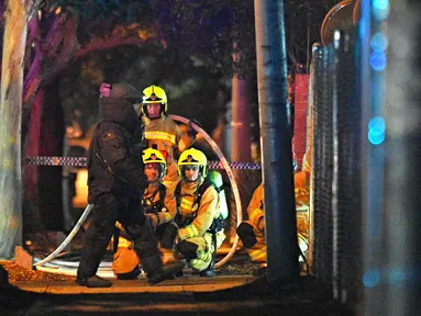 Tim gegana mengenakan pakaian pelindung setelah seorang pria yang mengendarai mobil berisi tabung gas dan menabrak pintu gerbang markas polisi Merrylands, Sydney Barat, Kamis (21/7). Pria itu sebelumnya mengklaim membawa bom. (AAP/Sam Mooy via REUTERS)