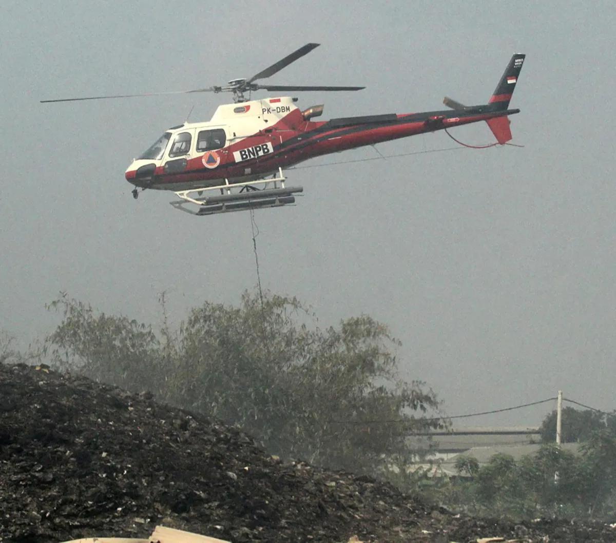 Helikopter Water Bombing  Badan Nasional Penanggulangan Bencana (BNPB) masih terus melakukan pemadaman api yang membakar tempat pembuangan akhir (TPA) Rawa Kucing, Neglasari, Kota Tangerang, Senin (23/10/2023).