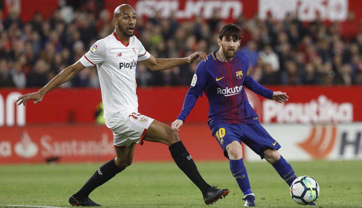 Pemain Barcelona, Lionel Messi (kanan) mengecoh pemain Sevilla, N'zonzi pada laga La Liga Santander di Sanchez Pizjuan stadium, (31/3/2018). Barcelona bermain imbang 2-2 dengan Sevilla. (AP/Miguel Morenatti)