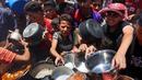 Warga Palestina berusaha mendapatkan makanan di dapur umum yang menyediakan makanan hangat di lingkungan Rimal, kota Gaza pada 18 Juni 2025. (Omar AL-QATTAA/AFP)