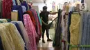 Pekerja menata bahan kain di Pasar Tanah Abang, Jakarta, Sabtu (27/11/2021). Utilisasi industri tekstil dan produk tekstil dalam negeri menunjukkan kinerja yang positif menjelang akhir 2021. Utilisasi industri itu berada di posisi 80 - 85 persen pada awal kuartal IV/2021. (Liputan6.com/Angga Yuniar)