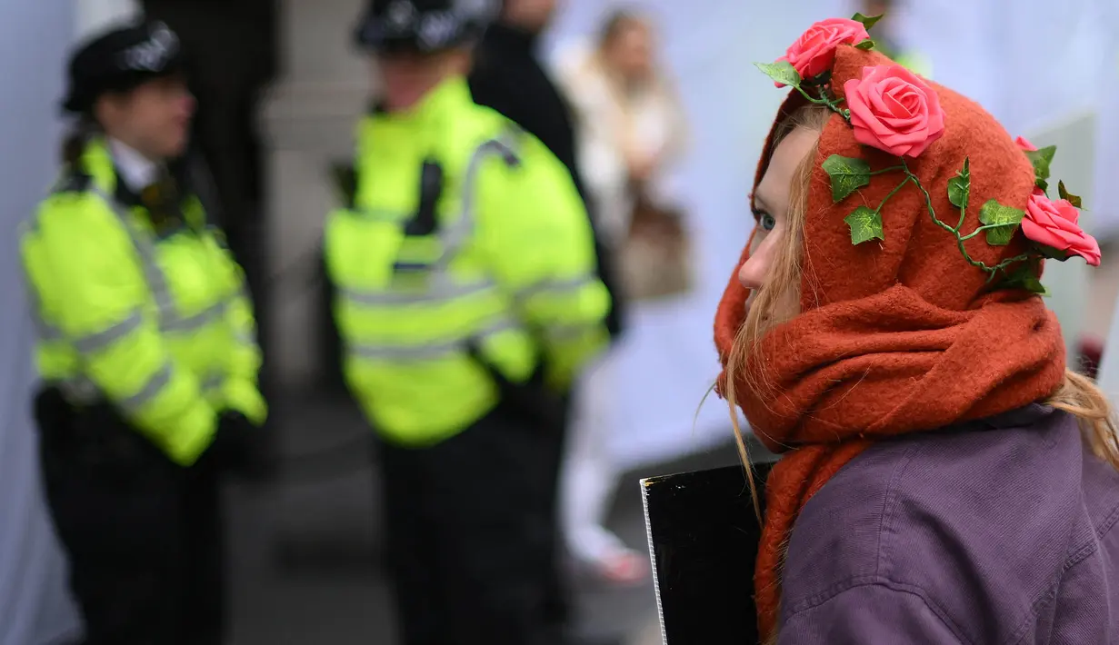 Seorang aktivis iklim yang mengenakan mahkota mawar ikut serta dalam protes menentang proyek ladang minyak Rosebank di Laut Utara di lepas pantai Skotlandia, di luar InterContinental London Park Lane, London, 18 Oktober 2023. (Daniel LEAL/AFP)