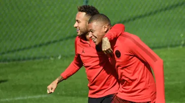 Pemain Paris Saint-Germain (PSG), Neymar (kiri) bercanda dengan Kylian Mbappe (kanan) saat sesi latihan di Paris Barat, Prancis, Senin (17/9). PSG akan menghadapi Liverpool di Liga Champions pada 19 September 2018. (FRANCK FIFE/AFP)