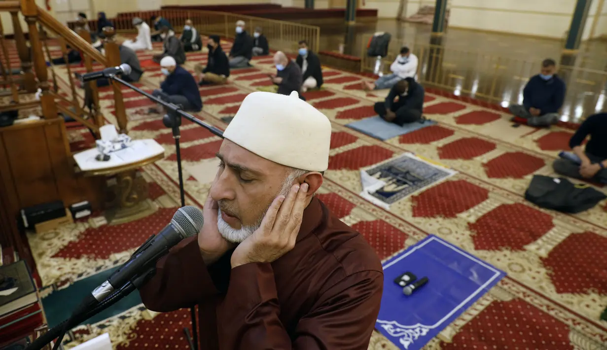 Yusuf Omar melakukan adzan sebelum melaksanakan tarawih pada malam pertama bulan suci Ramadhan di Pusat Komunitas Muslim Chicago, Senin (13/4/2021). (AP Photo/Shafkat Anowar)