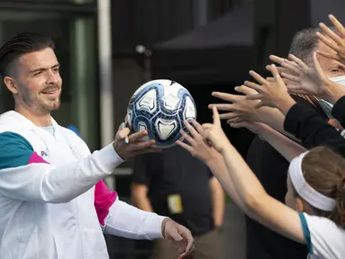 Pemain baru Manchester City, Jack Grealish, memberikan bola kepada para penngemar saat diperkenalkan di Stadion Etihad, Senin (9/8/2021). Manchester City memecahkan ekor transfer Inggris dengan mendatangkan Jack Grealish dari Aston Villa dengan harga £100 juta ($139 juta). (AP Photo/Jon Super)