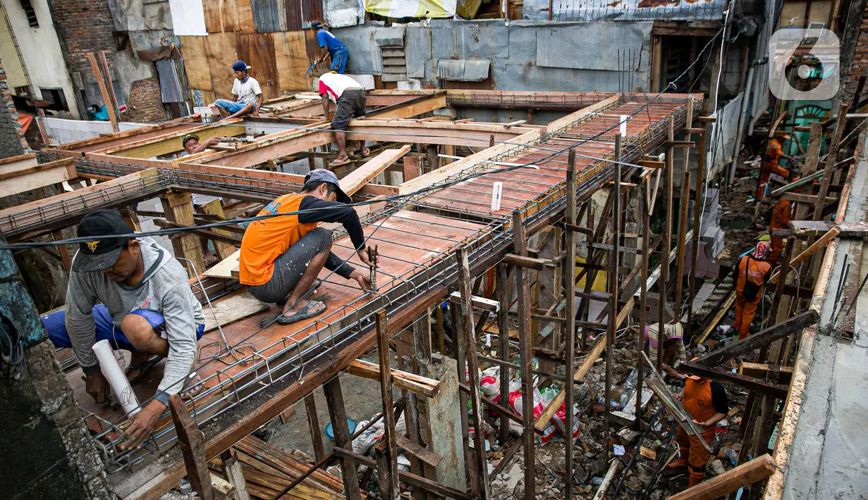 Para pekerja menyelesaikan pembangunan rumah panggung di dekat bantaran Kali Ciliwung, Kampung Melayu, Jakarta, Rabu (7/4/2021). Pemerintah Provinsi DKI Jakarta melakukan renovasi terhadap 40 hunian warga Kampung Melayu menjadi rumah panggung. (Liputan6.com/Faizal Fanani)