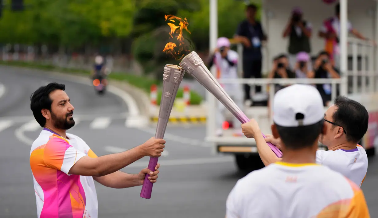 Seorang pembawa obor menyalakan api saat kirab obor Asian Games ke-19 di Hangzhou, China, Rabu, 20 September 2023. (AP Photo/Vincent Thian)