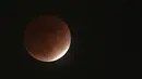 Bayangan bumi menutupi bulan saat gerhana bulan sebagian atau parsial di Yokohama, dekat Tokyo, Jepang, Jumat (19/11/2021). Gerhana bulan yang diamati pada tanggal 18 dan 19 November di berbagai wilayah dunia ini merupakan gerhana parsial yang terpanjang pada abad 21 ini. (AP Photo/Eugene Hoshiko)