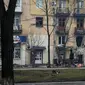 Seorang pria berjalan melewati sebuah gedung apartemen pada 2 Maret yang dirusak oleh penembakan Rusia di Mariupol, Ukraina. (Evgeniy Maloletka/AP)