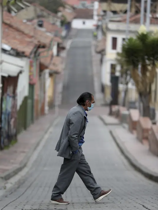 Pejalan kaki yang mengenakan masker menyeberang jalan di tengah lockdown yang diberlakukan kembali di Bogota, Kolombia, Sabtu (10/4/2021). Walikota Bogota Claudia Lopez memerintahkan lockdown hingga 13 April saat ibu kota mengalami peningkatan tajam infeksi COVID- 19. (AP Photo/Fernando Vergara)